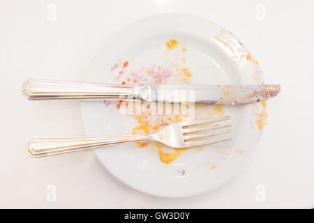 Empty white plate with crumbs and cream after eating Stock Photo