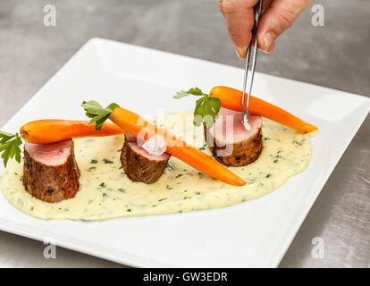 Chef adding finishing touch on his dish before it goes on the table. Stock Photo