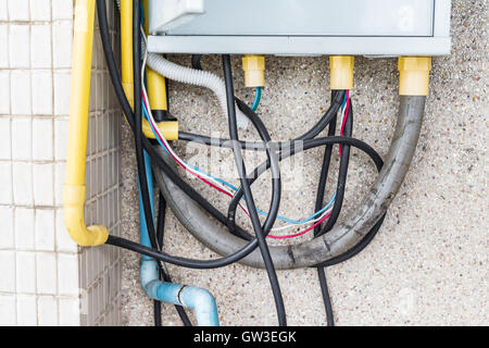 Too many Cable plugs in a socket on brick wall. Danger of using too much electricity. Stock Photo