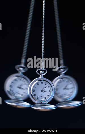 Pocket watch swinging on a chain to hypnotise , black background Stock Photo