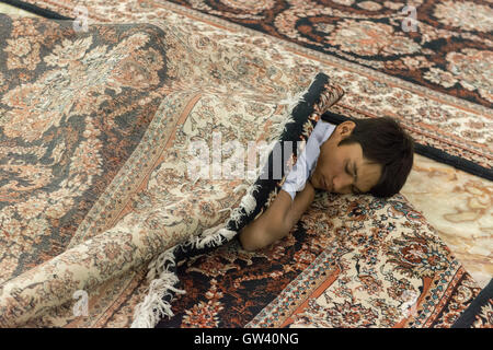 The Holy Shrine Of Imam Khomeini, Young Male Pilgrim Sleeping Between Carpets Stock Photo