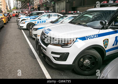 Police cars parked near a precinct in New York City. A fire truck is coming out on the street in the background. Stock Photo