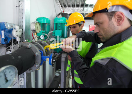 Two workers in hardhats at plant checking parameters of pressure Stock Photo