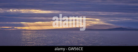 Crepuscular rays near sunset over the island of Santiago in the Galapagos Islands of Ecuador Stock Photo