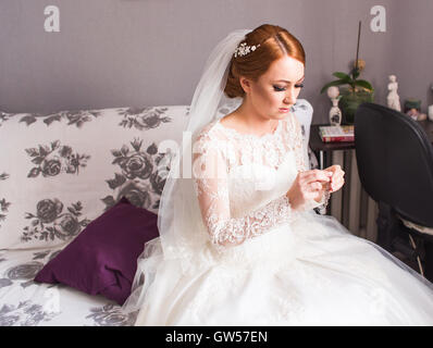 Elegant bride putting on earrings, preparing for wedding Stock Photo