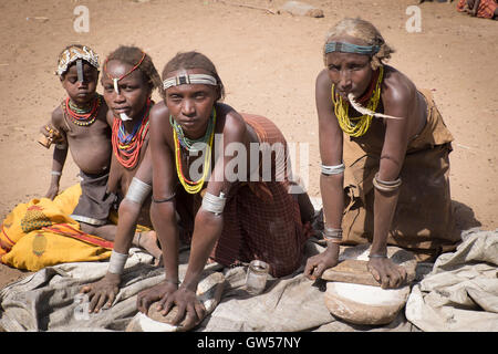 Four generations of the women of the Dasanech tribe in the Omo River Valley of southern Ethiopia grind sorghum for food Stock Photo