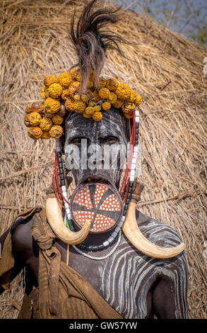 Mursi woman of the Omo Valley in Ethiopia with lip plate, body painting, headdress, feathers and bone earrings Stock Photo