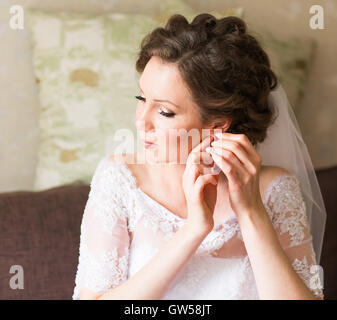 Elegant bride putting on earrings, preparing for wedding Stock Photo