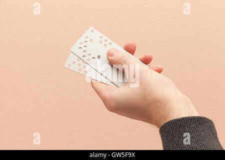 Male hand holds plastic door key cards with holes combination code Stock Photo