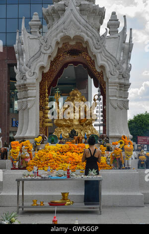 Devotee praying for luck at the Ganesha Shrine in Bangkok, Thailand Stock Photo