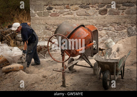 Albanian worker mixes cement for a construction job repairing a wall in Greece Stock Photo