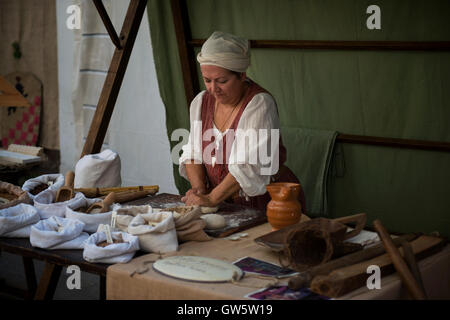 A traditional baker kneading dough at a market stand during the Medieval festival 'Macia' in Spilimbergo, northern Italy. Stock Photo