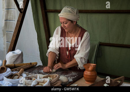 A traditional baker kneading dough at a booth during the commemoration of the 'Macia', a Medieval feast in Spilimbergo, Italy. Stock Photo