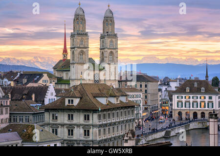 Zurich city center and cathedral towers with snow covered Alps mountains in background on sunset, Switzerland Stock Photo