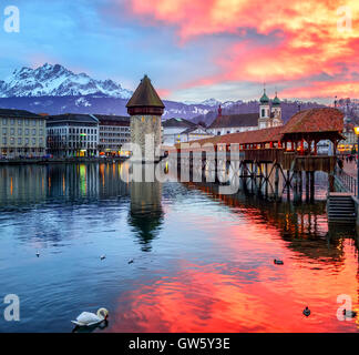 Dramatic sunset over the old town of Lucerne, Chapel Bridge, Water tower and snow covered Pilatus Mountain, Switzerland Stock Photo