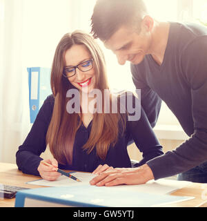 Two office workers discussing about papers at the desk. Corporate business people looking at contract having conversation Stock Photo