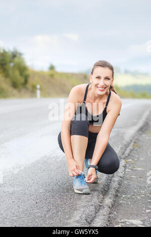 Young fitness woman lace up her trainers before jogging Stock Photo