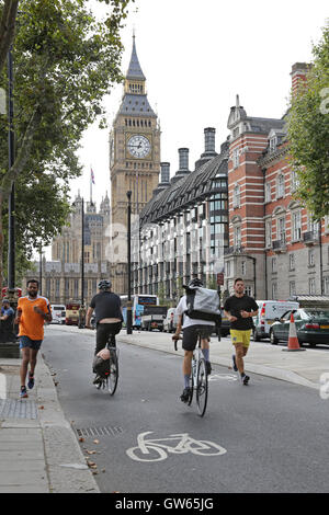 Cyclists and runners use the new east-west cycle superhighway along London's Victoria Embankment. Shows Big Ben in background Stock Photo