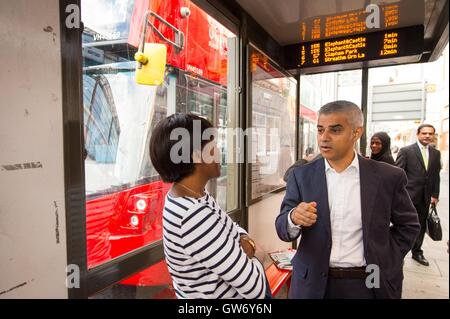 Mayor of London Sadiq Khan talks to a woman at a bus stop in Tooting, south London as he launches the one-hour London bus hopper ticket , which allows passengers to make two bus journeys in a one-hour window for one fare. Stock Photo