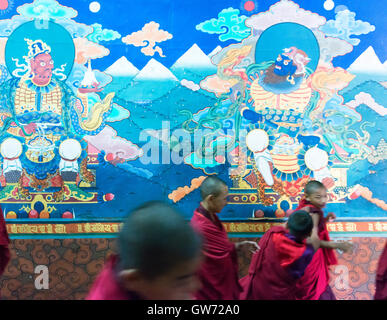 Novice monks walk past murals in Paro Dzong. Stock Photo