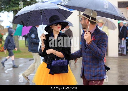 Visitors pictured in the bad weather, whilst in period dress at the Goodwood Revival this morning. Stock Photo