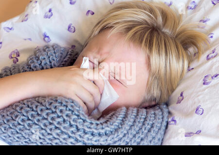 Sick little child boy blowing nose laying in bed with sad face - healthcare and medicine concept Stock Photo