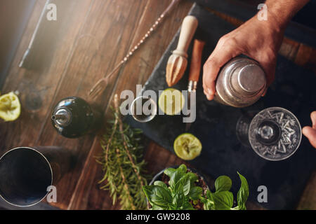 Top view shot of barman hand holding cocktail shaker on table with ingredients. Stock Photo