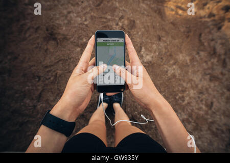 Woman checking the summary of her run on smartphone. POV shot of woman runner using a fitness app on her cellphone. Stock Photo