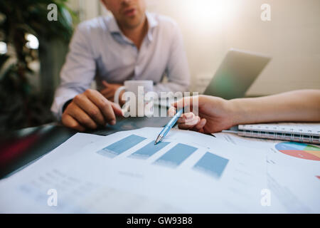 Close up shot of coworkers reviewing paperwork together in office. Businesspeople analyzing graphs during a meeting. Focus on fe Stock Photo