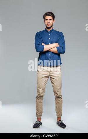 Handsome young casual man standing with hands crossed over gray background Stock Photo