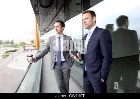 Two business people with coffee chatting on balcony of office building Stock Photo