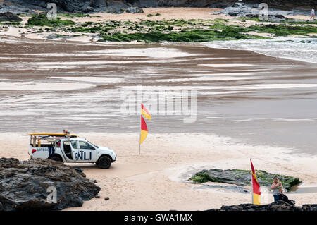 Lifeguards watching swimmers between red & yellow safety flags on the beach at Treyarnon Bay in Cornwall. Stock Photo