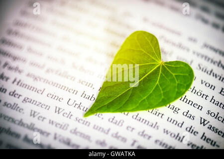 Heart-shaped sheet on a book page, Herzfoermiges Blatt auf einer Buchseite Stock Photo