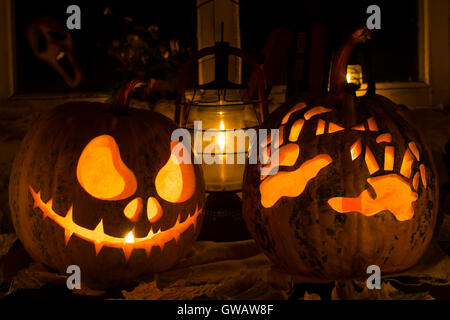 Photo composition from two pumpkins on Halloween. Jack and awful hands against an old window, dry leaves and a terrible ghost in Stock Photo