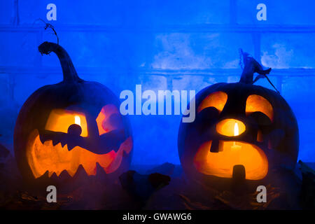 Photo composition from two pumpkins on Halloween. The embittered and crying pumpkins against a brick wall and a dense smoke Stock Photo