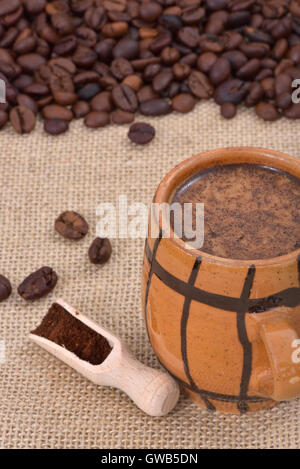 Vintage ceramic cup with coffee and milk on a jute with coffee beans in the background Stock Photo