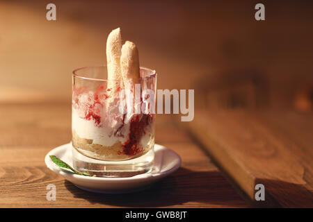 Cheesecake in a glass jar on a rustic wood background. Cheesecake half eaten. Stock Photo