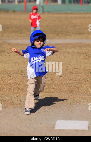 A young boy runs to third base during a game of baseball in Cairns, Australia Stock Photo