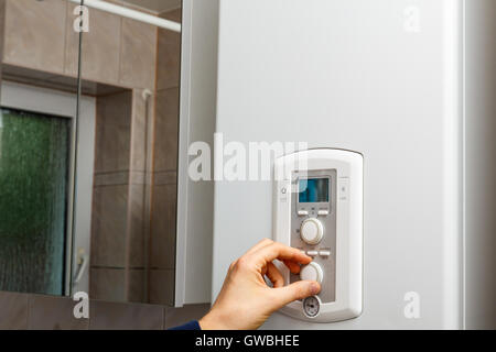 Men hand regulate temperature on DHW control panel. Stock Photo