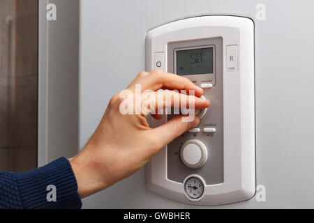 Men hand regulate temperature on 50 degree in control panel of central heating. Stock Photo