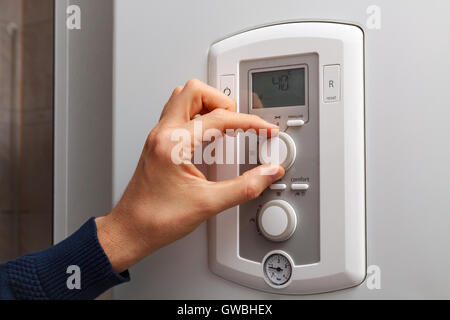 Men hand regulate low temperature on 40 degree in control panel of central heating. Stock Photo