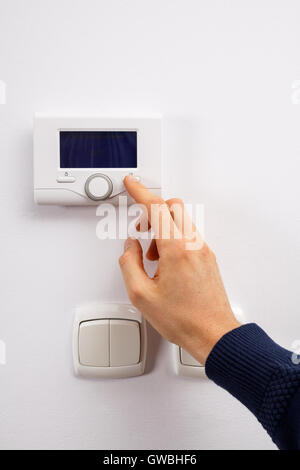 Men hand setting the temperature on control panel of DHW or central heating. Stock Photo