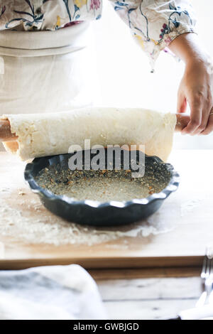 A woman puts pie dough in a baking pan Stock Photo