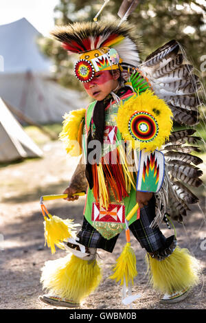 A young Native American dancer from the Arapahoe people dressed in traditional costume prepares to perform a fancy dance at the Indian Village during Cheyenne Frontier Days July 25, 2015 in Cheyenne, Wyoming. Frontier Days celebrates the cowboy traditions of the west with a rodeo, parade and fair. Stock Photo