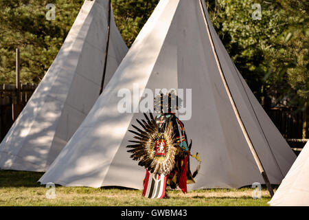 A Native American dancer from the Arapahoe people dressed in traditional costume returns to a teepee camp at the Indian Village during Cheyenne Frontier Days July 25, 2015 in Cheyenne, Wyoming. Frontier Days celebrates the cowboy traditions of the west with a rodeo, parade and fair. Stock Photo