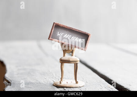 We're hiring written on chalkboard and chair Stock Photo