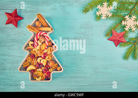 Retro toned Christmas tree shaped container filled with nuts and dried fruits on a rustic wooden table, top view with copy space Stock Photo