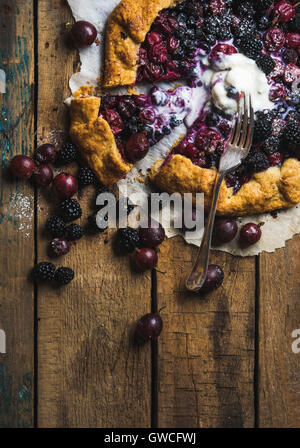 Homemade garden berry galetta or crostata sweet pie with melted vanilla ice-cream scoop served with fresh berries on rustic wood Stock Photo