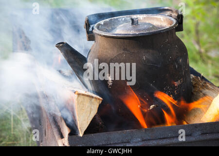 Old used black boiling teapot on bonfire Stock Photo