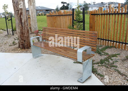 Ornate wooden garden bench seat on green lawn, Barnsdale 